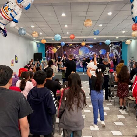 A crowd of children and adults gathering in a large hall decorated with space themes