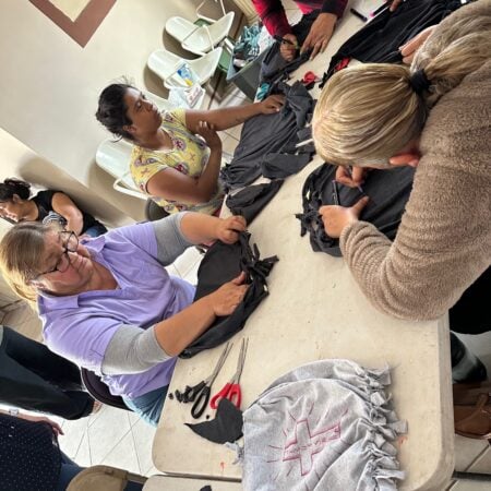 Women working together at a long table cutting and assembling fabrics