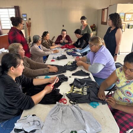 Multiple women gathered around a table working on a community craft project