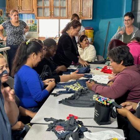 A large group of women working together at tables in a brightly lit room