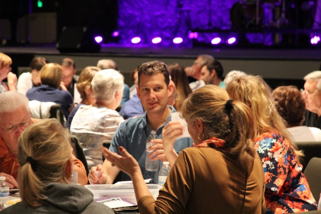 People gathered around a table during a conversation, sharing ideas, discussions, and meaningful connections