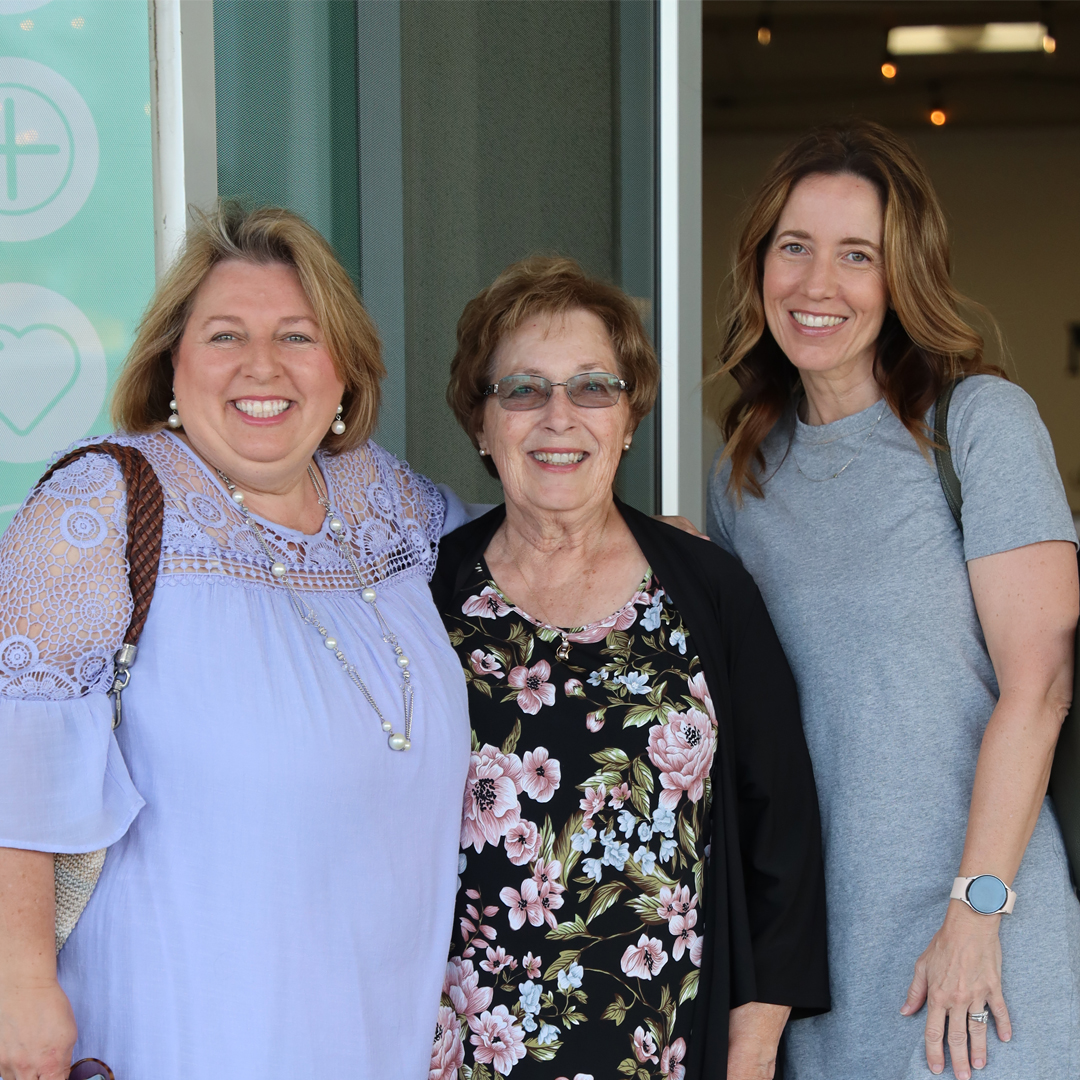 Three smiling women standing together at a New Covenant Women's Ministry event